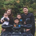 Happy family posing together outdoors with a quad bike