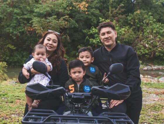Happy family posing together outdoors with a quad bike