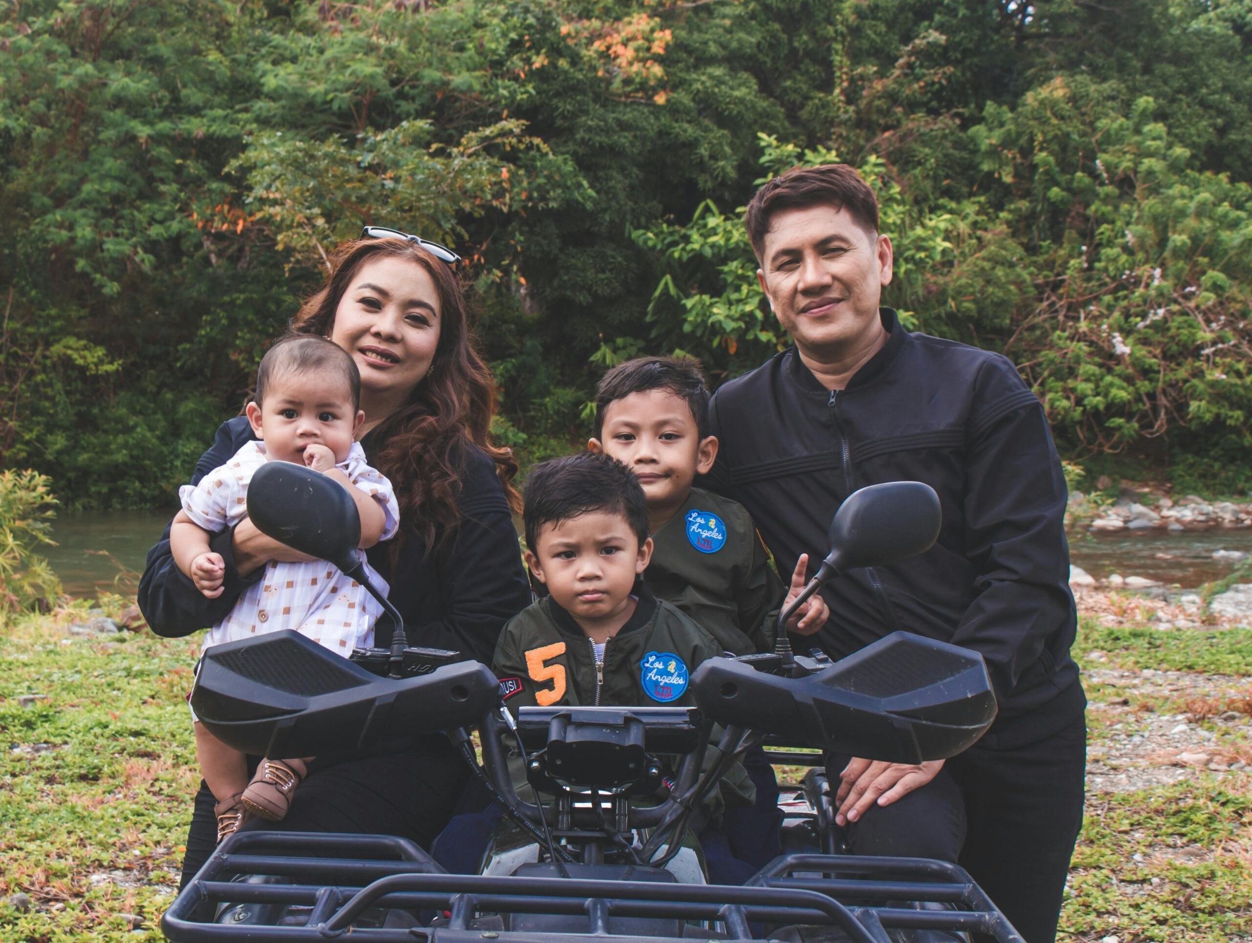 Happy family posing together outdoors with a quad bike