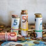 Close-up of rolled Euro banknotes and coins on a table, symbolizing finance and savings.