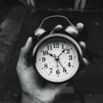 Close-up of a vintage clock held in hand, black and white with selective focus.