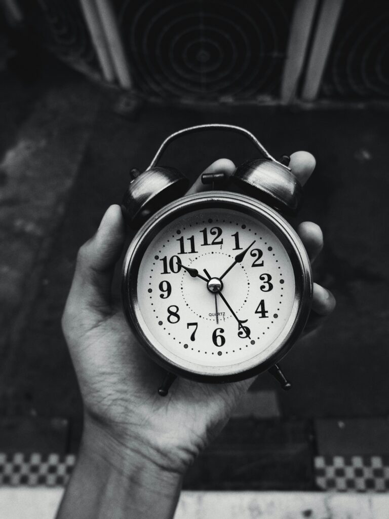 Close-up of a vintage clock held in hand, black and white with selective focus.
