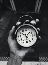 Close-up of a vintage clock held in hand, black and white with selective focus.