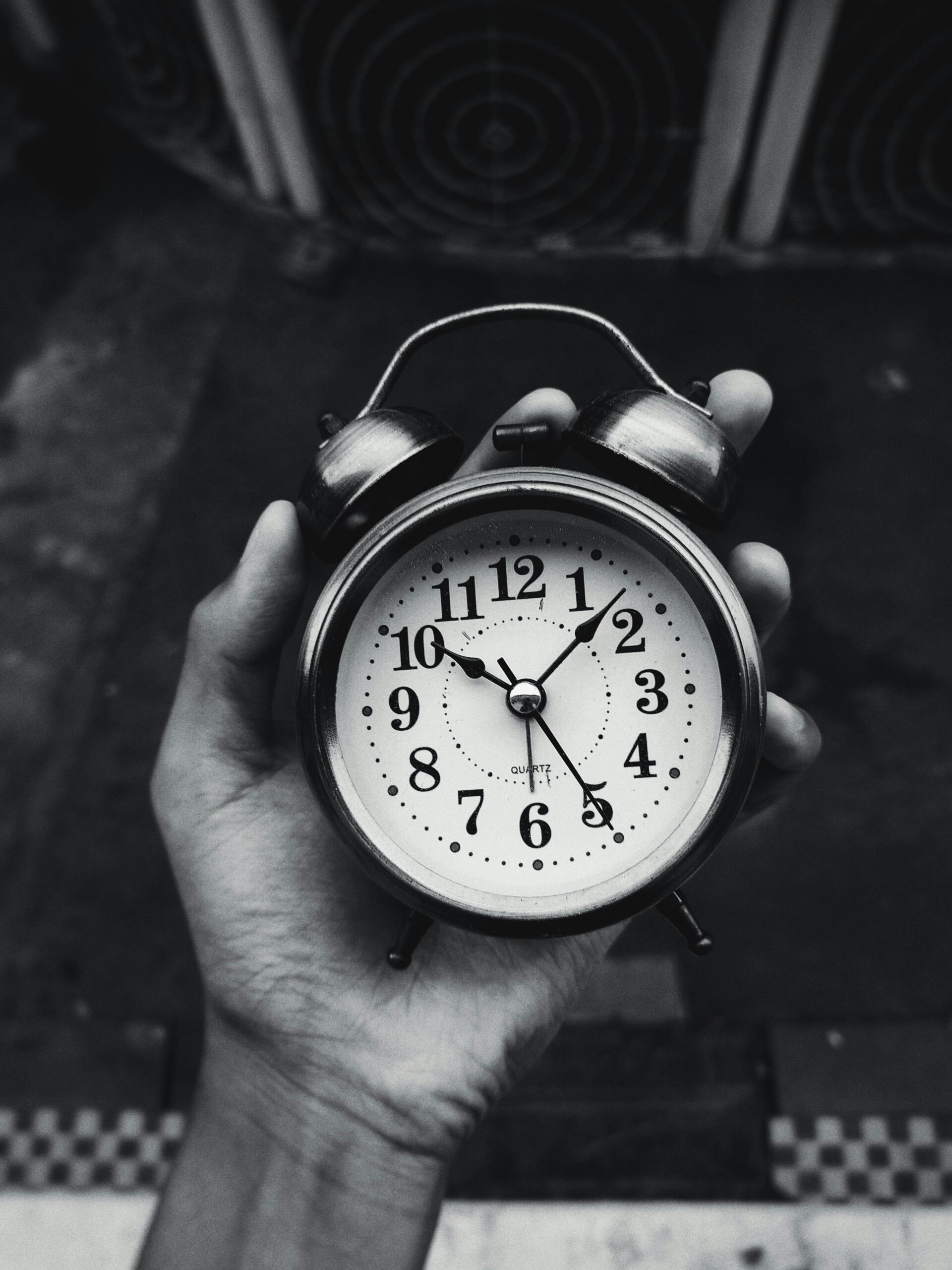 Close-up of a vintage clock held in hand, black and white with selective focus.