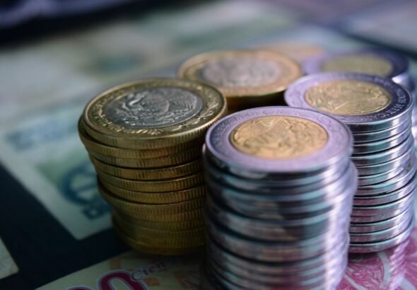 Close-up of stacked gold and silver coins on various currency notes, symbolizing wealth and savings.